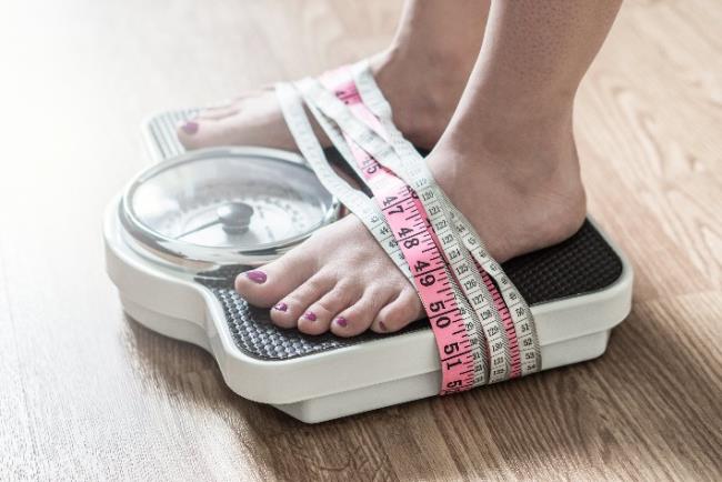רגליים של אישה על משקל לבדיקת BMI